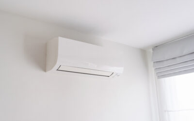 Air conditioner on white concrete wall in area of room.